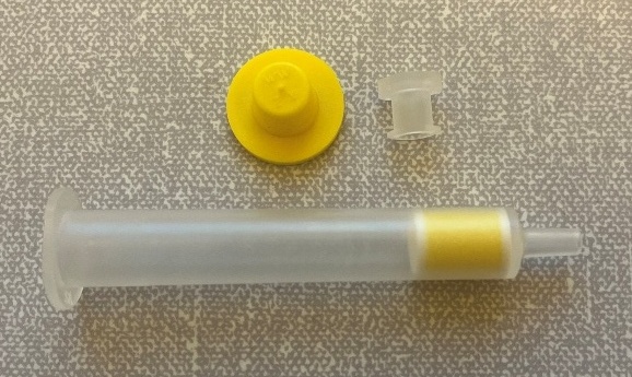 A plastic syringe with a yellow lid

Description automatically generated